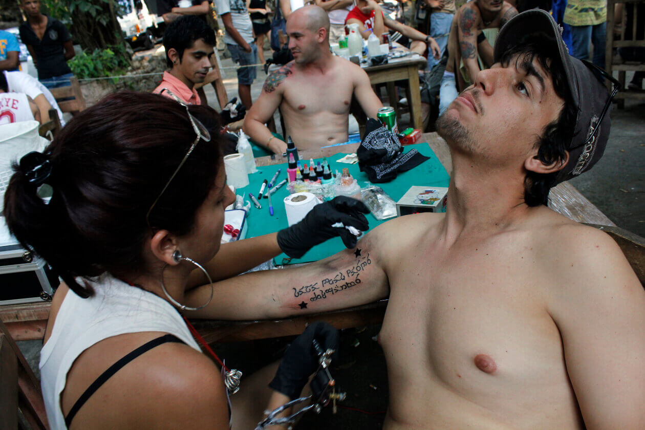 Una artista del tatuaje interviene el brazo de un joven durante el Festival Peace and Love, celebrado en Puentes Grandes, uno de los municipios que integran La Habana, en Cuba. Crédito: Jorge Luis Baños | IPS